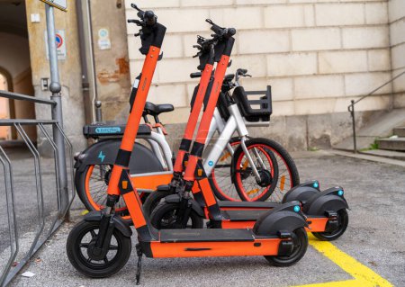 Foto de Servicio de suscripción de alquiler de bicicletas eléctricas y scooter eléctrico en el aparcamiento urbano en la ciudad - concepto de transporte urbano sostenible ecológico - Imagen libre de derechos