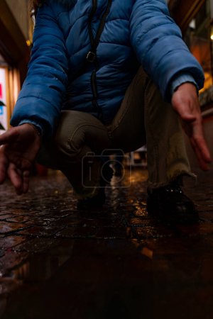 Photo for Female feet in blue sneakers are reflected in a puddle of a city street in the evening - Royalty Free Image