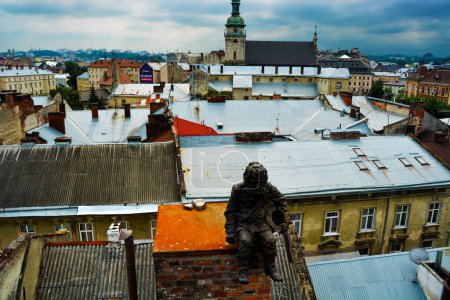 Photo for Photo of Bronze sculpture of the Chimney sweep on the roof of a house in Lviv with a beautiful view of the city - Royalty Free Image