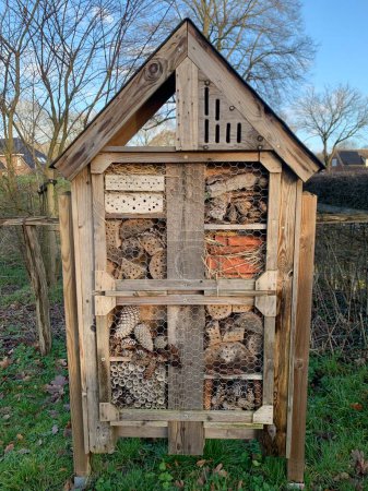 Foto de Bee hotel in garden. A bee hotel is an artificial structure for the nests of solitary bees - Imagen libre de derechos
