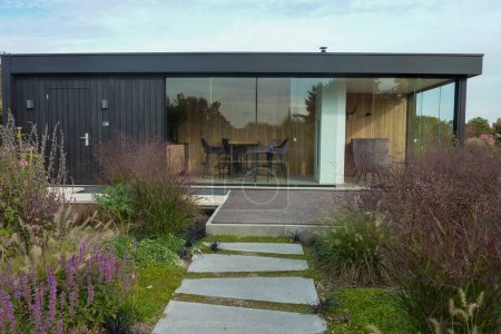 Téléchargez les photos : Beautiful luxury mobile cottage in garden. Appeltern, Netherlands, October 12, 2022: Appeltern is the Netherlands' largest garden idea park. Modern building with green plants. The country house is easily transferred to any other place - en image libre de droit