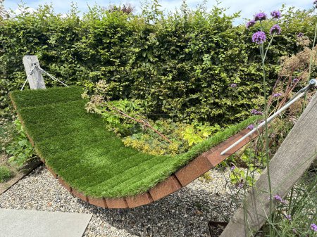 Téléchargez les photos : Balançoire couverte d'herbe vivante dans le jardin. Corten planteurs de fleurs en acier - en image libre de droit