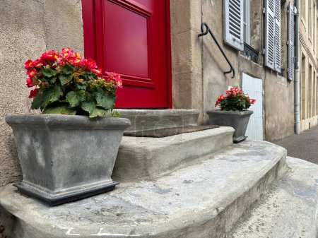 Foto de Casa de entrada con puerta roja y begonia roja en macetas de estilo romano. Francia, Borgoña, Autun - Imagen libre de derechos