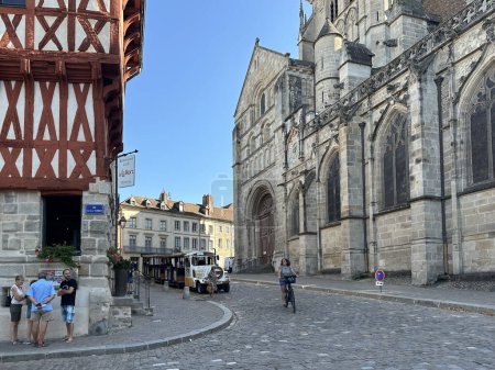 Téléchargez les photos : Autun, France, 02 août 2023 : Cathédrale Saint-Lazare, restaurateur, train touristique d'excursion et personnes dans la vieille rue pavée - en image libre de droit