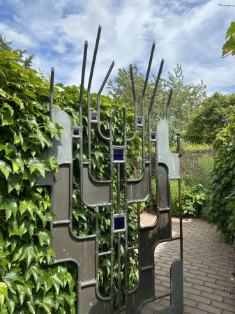Appeltern, Netherlands, July 11, 2023: Appeltern adventure garden. Decorative wrought iron gate framed by a cascade of vine leaves