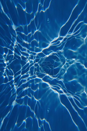Téléchargez les photos : Défocus flou transparent bleu clair texture de surface de l'eau calme avec éclaboussures et bulles. Fond nature abstrait à la mode. Ondes d'eau au soleil avec espace de copie. Aquarelle bleue brillante - en image libre de droit