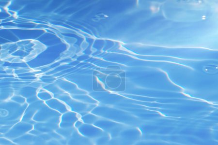 Photo for Defocus blurred transparent blue colored clear calm water surface texture with splashes and bubbles. Trendy abstract nature background. Water waves in sunlight with copy space. Blue watercolor shining - Royalty Free Image