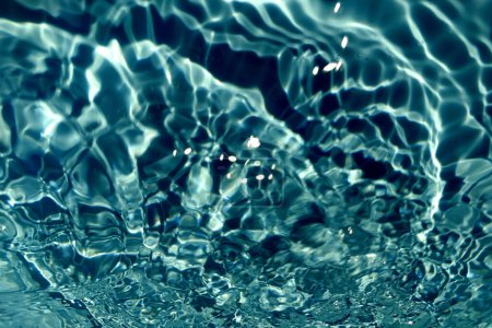 Defocus verschwommen transparent blau gefärbt klare ruhige Wasseroberfläche Textur mit Spritzern und Blase. Trendige abstrakte Natur Hintergrund. Wasserwelle im Sonnenlicht mit Kopierraum. Blaues Aquarell leuchtet.