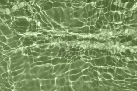 Desenfoque borrosa transparente de color verde claro textura de la superficie del agua calma con salpicaduras y burbujas. Fondo de naturaleza abstracta de moda. Ondas de agua a la luz del sol con espacio para copiar. Acuarela azul brillo
