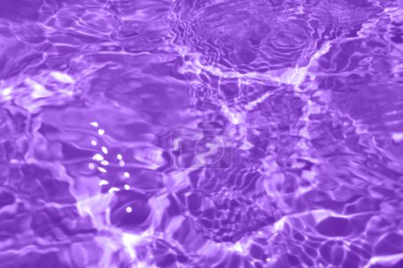 Téléchargez les photos : Défocus flou transparent violet clair texture de surface de l'eau calme avec éclaboussures et bulles. Fond nature abstrait à la mode. Ondes d'eau au soleil avec espace de copie. Rose goutte d'eau brillance - en image libre de droit