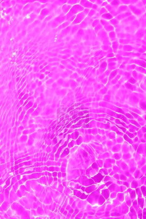 Téléchargez les photos : Défocus flou transparent violet clair texture de surface de l'eau calme avec éclaboussures et bulles. Fond nature abstrait à la mode. Ondes d'eau au soleil avec espace de copie. Rose goutte d'eau brillance - en image libre de droit