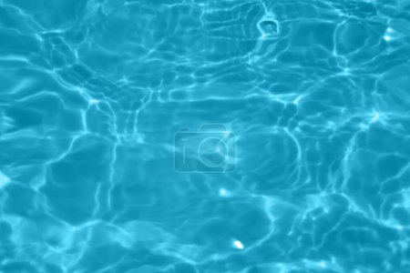 Foto de Desenfoque borrosa transparente de color azul claro textura de la superficie del agua calma con salpicaduras y burbujas. Fondo de naturaleza abstracta de moda. Ondas de agua a la luz del sol con espacio para copiar. Acuarela azul brillante - Imagen libre de derechos