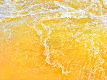 Defocus verschwommen transparent orange gefärbt klare ruhige Wasseroberfläche Textur mit Spritzer, Blase. Leuchtend orangefarbenes Wasser plätschert vor sich hin. Wasseroberfläche im Schwimmbad. Orangefarbenes Sprudelwasser.
