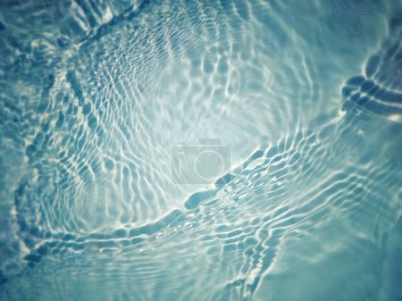 Defocus verschwommen transparent blau gefärbt klare ruhige Wasseroberfläche Textur mit Spritzern und Blasen. Trendige abstrakte Natur Hintergrund. Wasserwellen im Sonnenlicht mit Laugen. Blaues Wasser leuchtet 