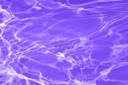Defocus blurred transparent purple colored clear calm water surface texture with splashes and bubbles. Trendy abstract nature background. Water waves in sunlight with copy space. Purple velvet.