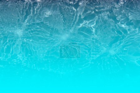 Foto de Agua azul con ondas en la superficie. Desenfoque borrosa transparente de color azul claro textura de la superficie del agua calma con salpicaduras y burbujas. Ondas de agua con brillante patrón de textura de fondo. - Imagen libre de derechos