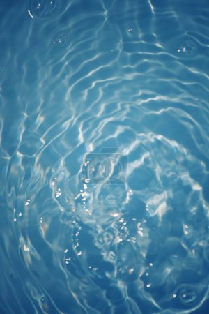 Téléchargez les photos : Eau bleue avec des ondulations à la surface. Défocus flou transparent bleu clair texture de surface de l'eau calme avec éclaboussures et bulles. vagues d'eau avec motif brillant texture fond. - en image libre de droit