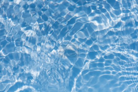 Ondes d'eau bleue sur les ondulations de surface floues. Défocus flou transparent bleu clair texture de surface de l'eau calme avec éclaboussures et bulles. vagues d'eau avec motif brillant texture fond.