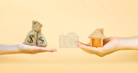 Téléchargez les photos : Loans for real estate concept, a man and a woman hand holding a money bag and a model home put together. planning savings money of coins to buy a home concept for property mortgage. Home loan. - en image libre de droit
