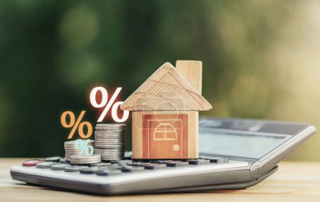Téléchargez les photos : Coins and house  on the calculator And has an illustration of interest concept of calculating interest payments. planning savings money of coins to buy a home concept for property, mortgage, invest. - en image libre de droit