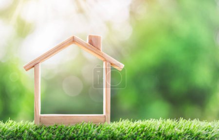 Musterhaus-Platz aus Holz auf der Wiese. Konzept der Immobilieninvestitionen. Planung von Ersparnissen in Münzen, um ein Eigenheimkonzept für Immobilien, Hypotheken und Immobilien zu kaufen, Ersparnisse für ein Haus.