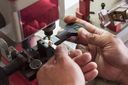 Photo for Locksmith in workshop makes new key. Professional making key in locksmith. Machine production of duplicate metal key. - Royalty Free Image
