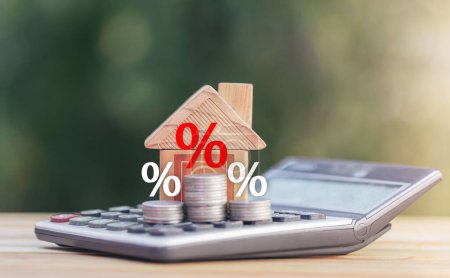 Téléchargez les photos : Coins and house  on the calculator And has an illustration of interest concept of calculating interest payments. planning savings money of coins to buy a home concept for property, mortgage, invest. - en image libre de droit