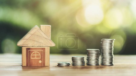 Haus und Münzen auf dem Holztisch. Konzept der Immobilieninvestitionen. Die Planung Spargeld von Münzen, um ein Wohnkonzept zu kaufen. Konzept für Immobilien-, Hypotheken- und Immobilieninvestitionen.