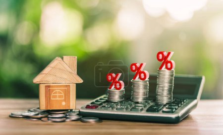 House is placed on the coins. coins on the calculator and has an illustration of interest concept of calculating interest payments. savings money of coins to buy a home concept for property, mortgage.