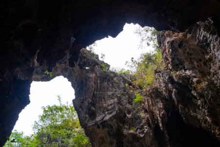 Foto de Vista de ángulo bajo de una salida de cueva oscura con luz solar que fluye en el eje de la cueva. - Imagen libre de derechos