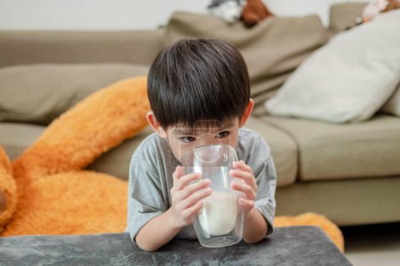 Téléchargez les photos : Asiatique garçon est boire un verre de lait - en image libre de droit