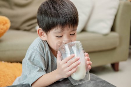 Téléchargez les photos : Asiatique garçon est boire un verre de lait - en image libre de droit