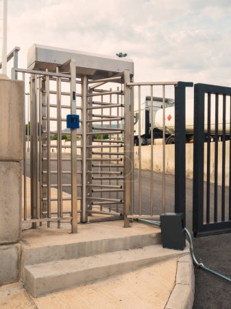 Téléchargez les photos : Porte d'accès sécurisée à une zone industrielle restreinte avec un lecteur optique et un camion sur le fond avec un contenu inflammable - en image libre de droit
