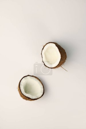 Photo for Exotic fruit of the coconut tree brown coconut with fibers and snow-white flesh on a light white background and green mint leaves. for advertising banners, labels, menu splash screens, and more - Royalty Free Image