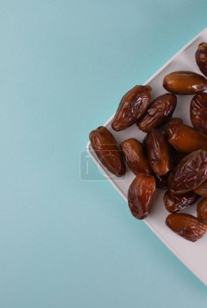 Photo for Fruits of a tropical date tree ripe sweet fragrant colorful dates of different varieties and like dried fruits on a light mint background. for screensavers labels signs banners flyers and more - Royalty Free Image