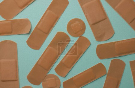 Photo for Medical plaster of brown color and different sizes from to protect wounds and from pain in the back, neck, on a light mint background - Royalty Free Image