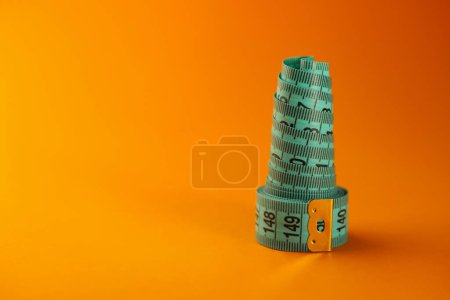 Photo for On a bright orange background, a blue sewing centimeter and a juicy orange horizontally and vertically. for banners, flyers, splash screens, signs, labels, advertisements, etc. - Royalty Free Image