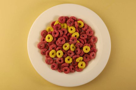 delicioso dulce saludable desayuno copos de maíz en anillos de diferentes colores amarillo y rosa en diferentes fondos. para presentaciones publicitarias, etiquetas, menús, banners y más