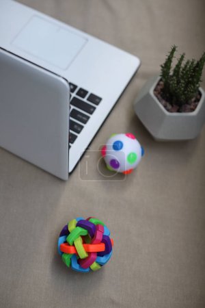 Téléchargez les photos : A white laptop is on the table and next to it is a homemade green plant and rubber balls to relieve stress of a bright neon color - en image libre de droit