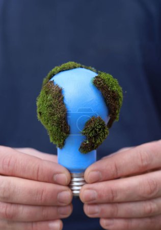 social problems. Earth Day. a blue light bulb with green moss is protected in the hands of a man