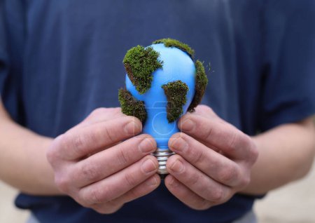 social problems. Earth Day. a blue light bulb with green moss is protected in the hands of a man