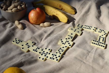 jeu de dominos à un pique-nique. loisirs. Il y a un domino sur le pique-nique et à proximité il y a des noix, des pommes, de l'eau et des bananes pour une collation saine.