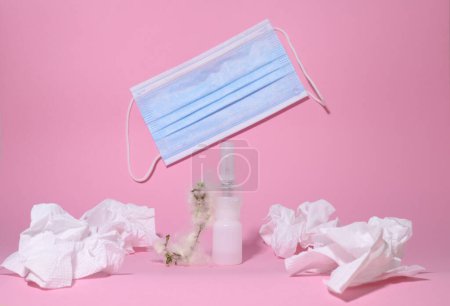 Allergie. Krankheit. auf rosa Hintergrund, eine weiße Flasche mit Medikamenten und einem Zweig mit Flaum, Servietten für die Nase und eine medizinische Gesichtsmaske