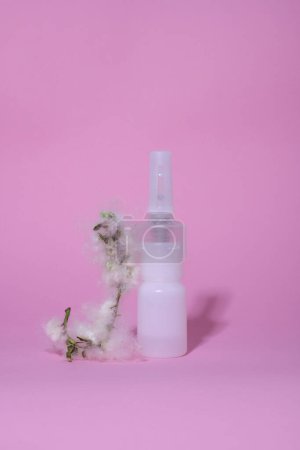 allergy. disease. on a pink background there is a white bottle with medicine and a twig with fluff