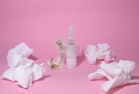 Allergie. Krankheit. auf rosa Hintergrund, eine weiße Flasche mit Medikamenten und einem Zweig mit Flaum, Servietten für die Nase und eine medizinische Gesichtsmaske