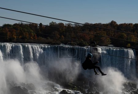 Foto de Una persona disfrutando de una aventura de tirolina en Niagara Falls, Ontario, Canadá en el otoño. Las Cataratas Americanas están en el fondo. - Imagen libre de derechos