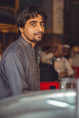 Retrato de un pobre paquistaní de mediana edad, Pathan, mirando a la cámara, trabajando en su tienda