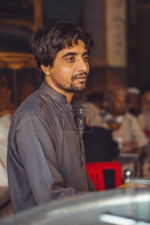 Retrato de un hombre paquistaní de mediana edad pobre, Pathan, trabajando en su tienda