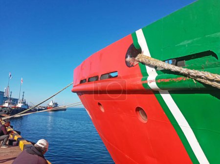 rot-grüner Bug eines Schiffes, das mit einem Seil an der Seebrücke festgemacht hat
