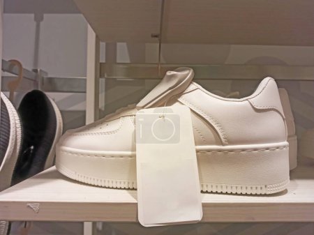 White women's sneakers with a tag lie on a shelf in a supermarket
